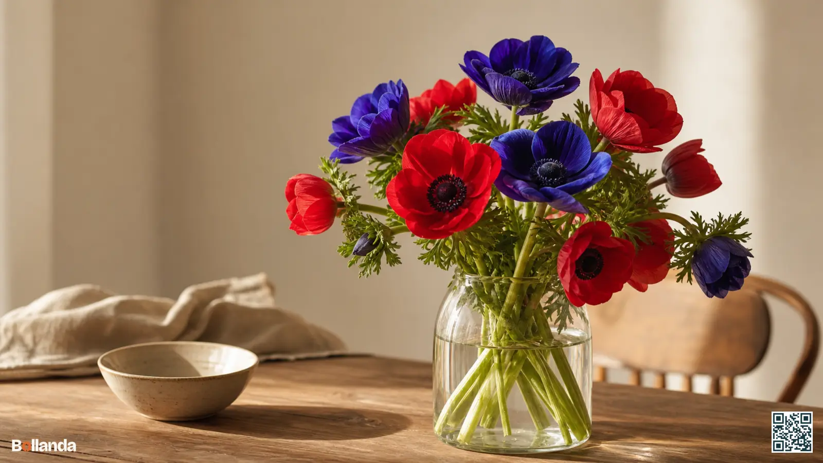 Vers gesneden kroonanemonen in blauw en rood in een glazen vaas op een houten tafel.